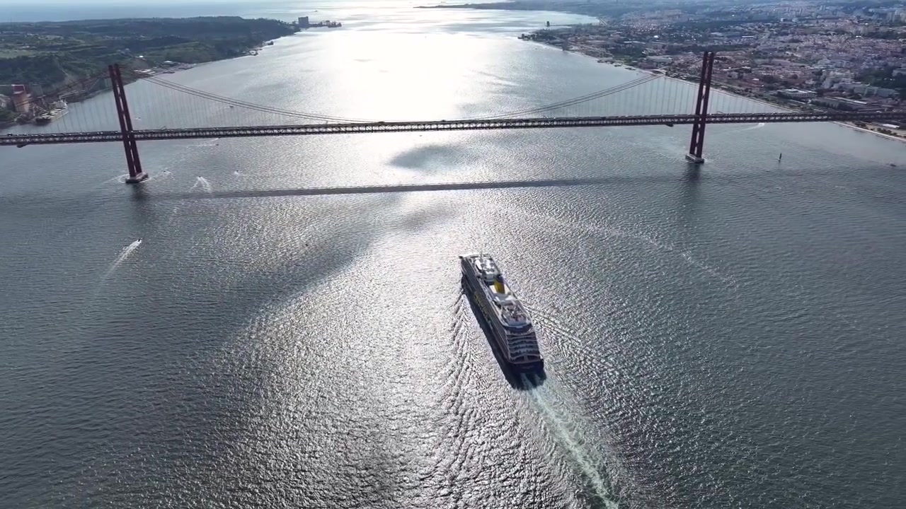 Maravíllate con el impresionante paisaje mientras un lujoso crucero se desliza elegantemente bajo un puente magnífico. Sé testigo de la belleza de los viajes oceánicos y de momentos serenos en este viaje de vacaciones.