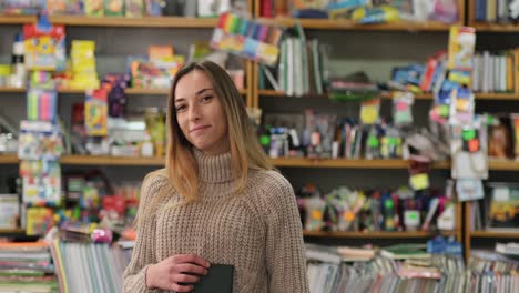 smart girl holding a book in her hands in the library and smiling