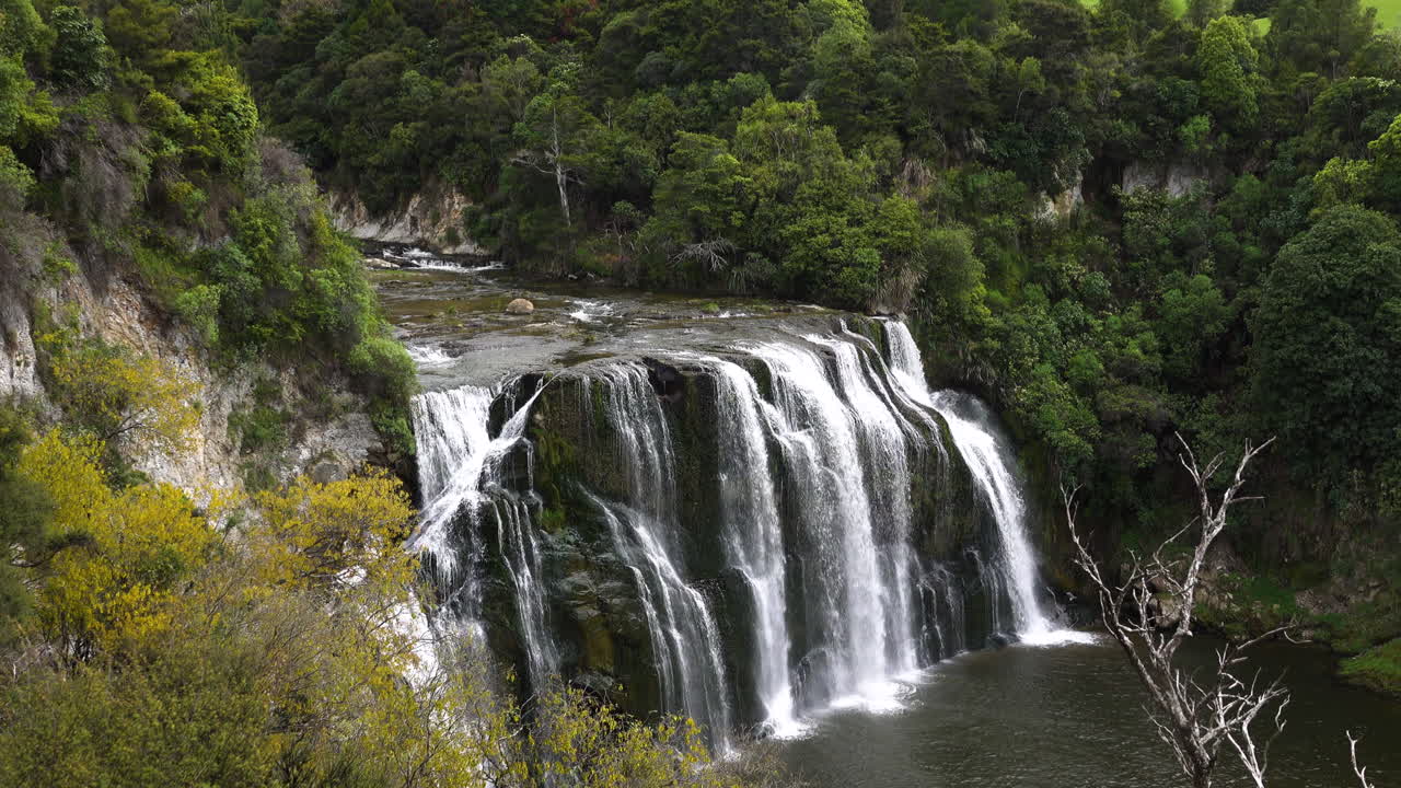 toma aérea de una gran cascada de waihi rodeada de paisajes verdes en la reserva de nueva zelanda - toma amplia