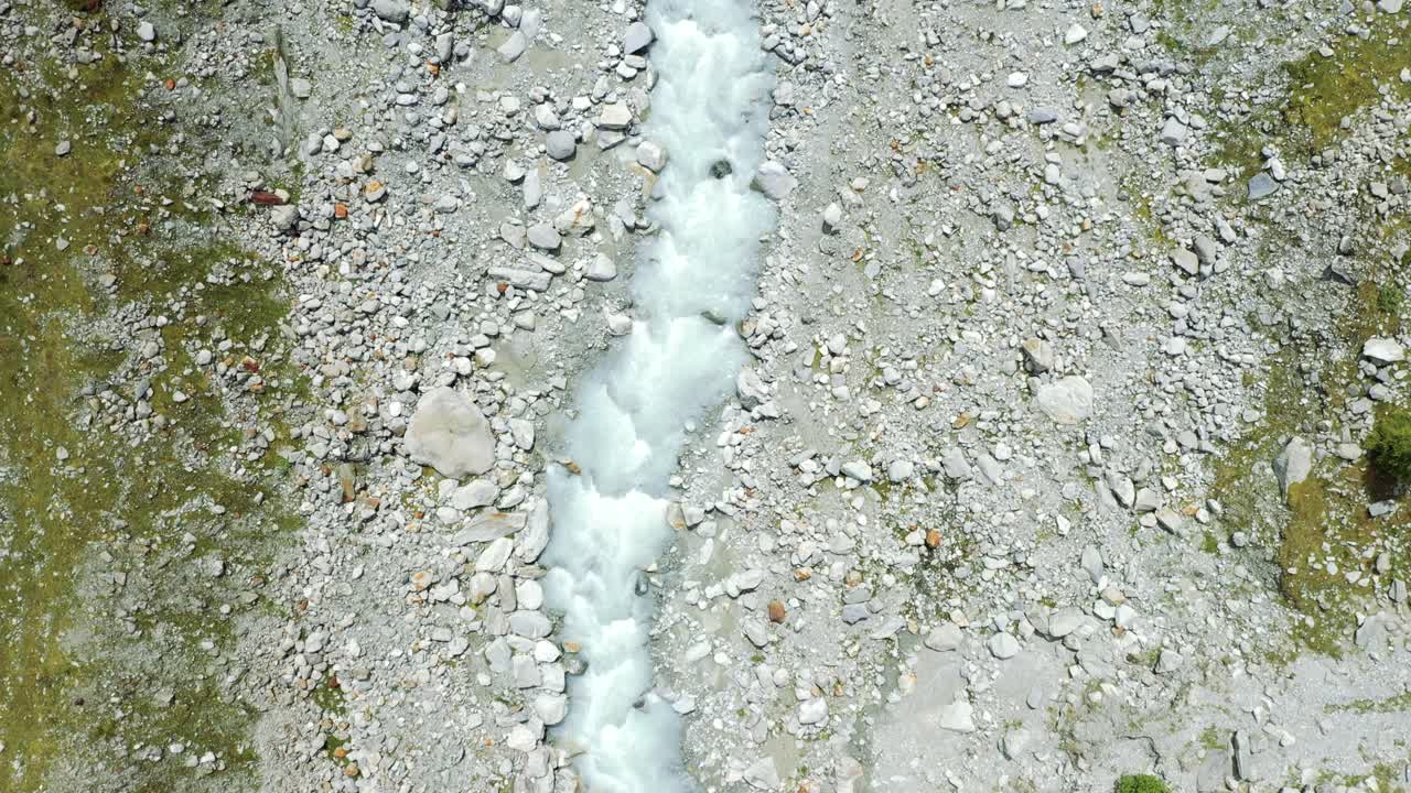 Volo di drone su un tortuoso fiume glaciale attraverso un'alta valle alpina di montagna.