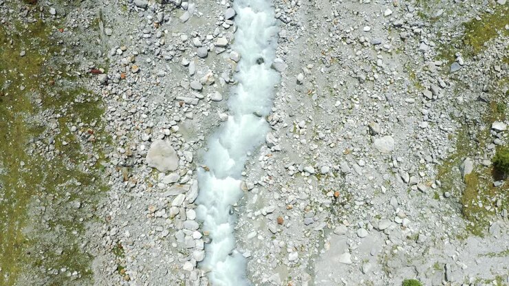 Volo di drone su un tortuoso fiume glaciale attraverso un'alta valle alpina di montagna.