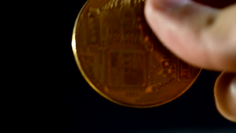 un hombre sostiene en sus manos un bitcoin dorado.