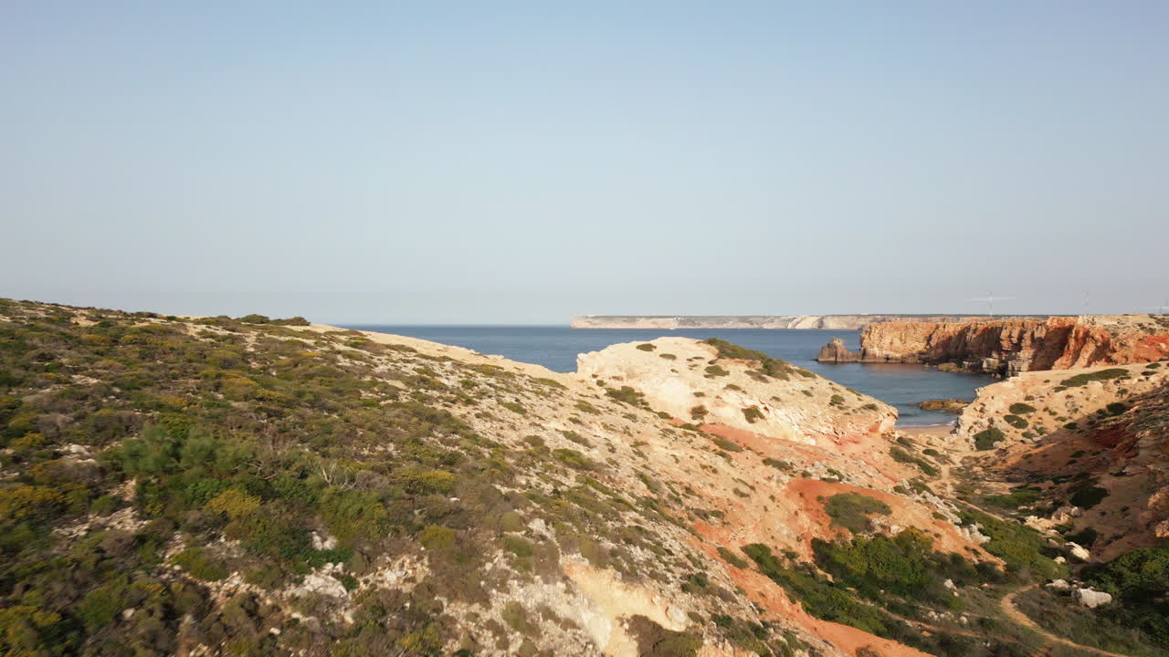Low drone shot over the cliffs revealing the beach at Tonel Sagres