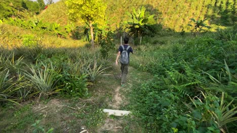 Following-backpacker-young-man-from-behind,-wondering-through-hilly-landscape