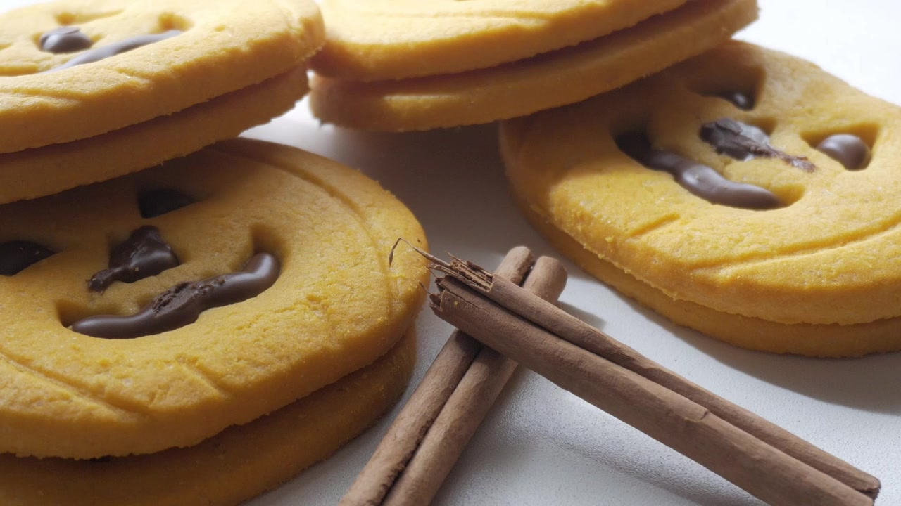 Close up of halloween cookies, looking like pumkins with a face made out of chocolate, zoom out, sweets fpr holiday