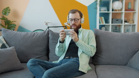 man playing mobile game on couch