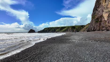 people walking on shingle beach older high cliffs on a spring day at ballydwane copper coast in waterford ireland