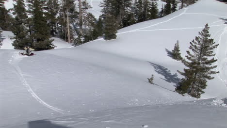 Mittlere-Aufnahme-Eines-Snowboarders,-Der-Vorbeifährt-Und-Pulver-Auf-Der-Linse-Der-Kamera-Hinterlässt