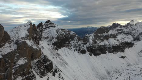 Toma-Aérea-Volando-Lentamente-Hacia-Atrás-Sobre-Una-Montaña-Cubierta-De-Nieve-Y-Agradable