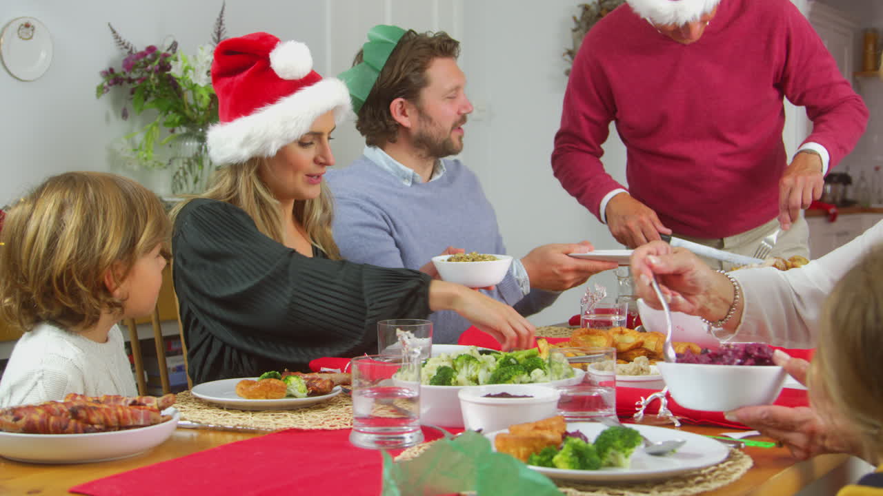 abuelo tallando y sirviendo pavo como una familia de varias generaciones comiendo la comida de navidad juntos