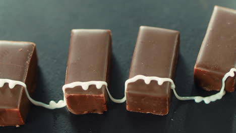 Sugar-syrup-pouring-on-dark-chocolate-candies.-Bonbons-with-cream-icing.