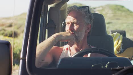 Nachdenklicher-Kaukasischer-Mann,-Der-An-Einem-Sonnigen-Tag-Am-Strand-Im-Auto-Sitzt-Und-Wegschaut