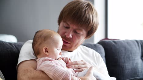 Careful-dad-sitting-on-couch-and-holding-baby