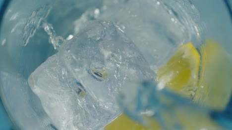 agua crujiente que se vierte en un vaso alto con hielo y limón