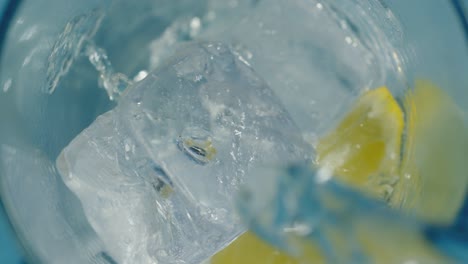 crisp water pouring into tall glass with ice and lemon