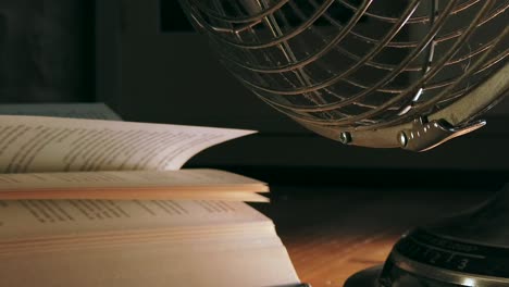 Close-up-low-angle-of-an-electric-fan-blowing-the-open-pages-of-a-book