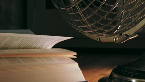 close up low angle of an electric fan blowing the open pages of a book