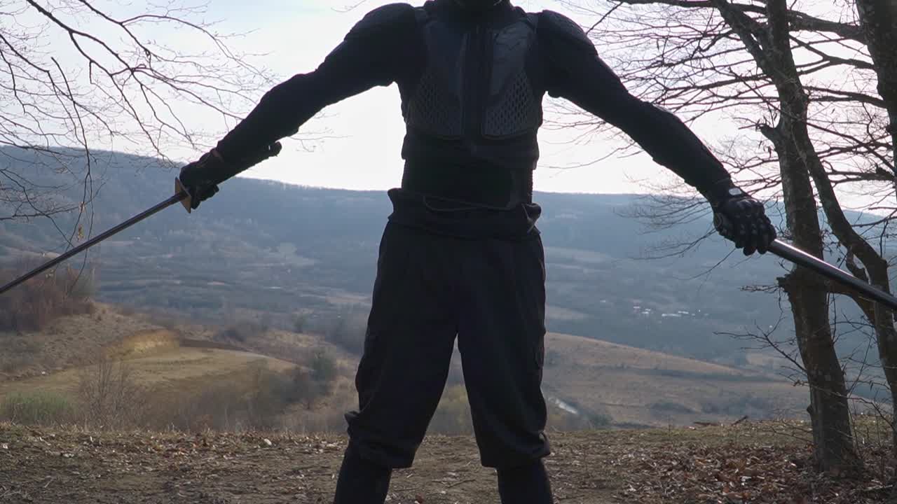 Dynamic stock image of an artisan in dark attire in a natural setting, engaged in the traditional folding technique of his katana, exuding martial precision and cultural heritage.