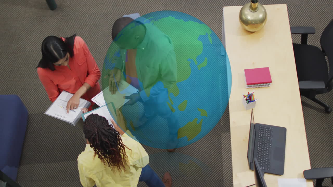 Diverse team collaborating at office with digital globe animation overlay
