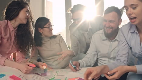 grupo de compañeros de trabajo haciendo una pancarta y hablando entre ellos en la oficina