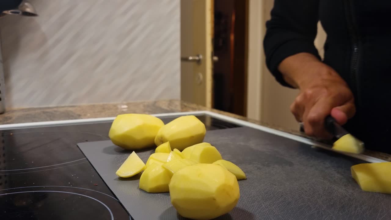 Close-up of hands chopping potatoes into small pieces in a warm Swiss kitchen, creating a wholesome, easy, and affordable homemade meal
