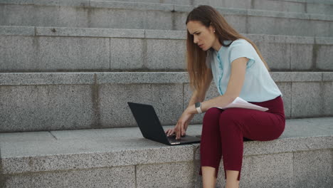 mujer de negocios trabajando en una computadora portátil afuera. ejecutivo escribiendo en una computadora portátil en la calle