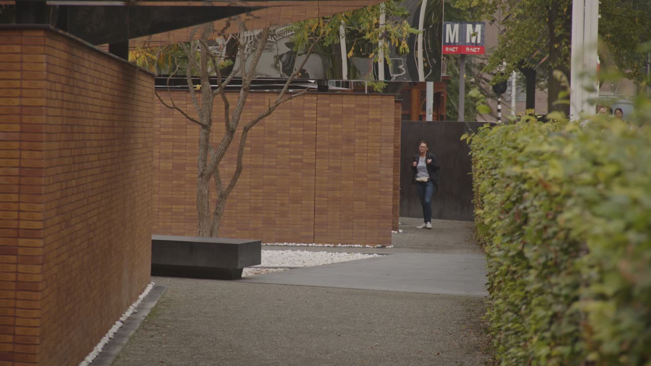 Wide view of woman walking past wall of National Holocaust Names Memorial in Amsterdam, the Netherlands