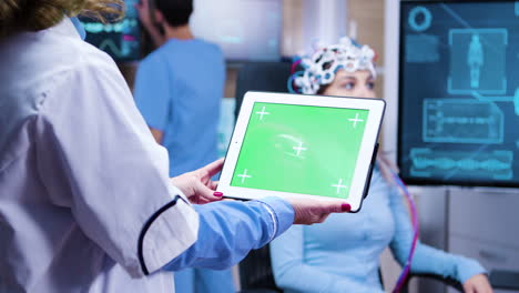 Female-doctor-holding-tablet-with-green-screen-in-a-modern-neurology-lab-science