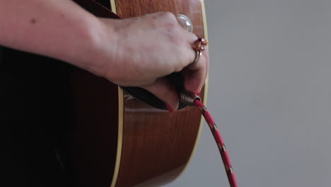 Woman-plugging-guitar-lead-into-electro-acoustic-guitar