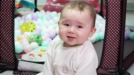 hungry angry infant baby showing off her unhappy face and waving hands while sitting on the floor room appartment