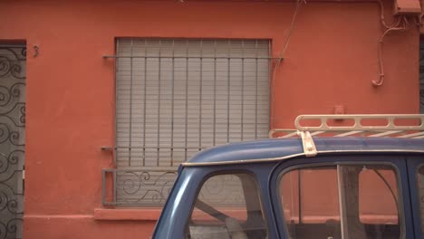 small vintage car parked near iconic looking building wall in city downtown