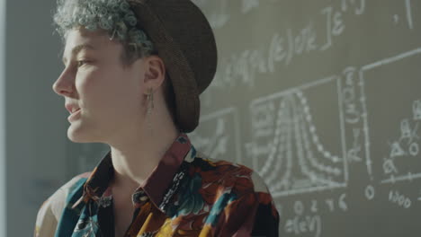 young adult with blue hair and hat pondering scientific formulas