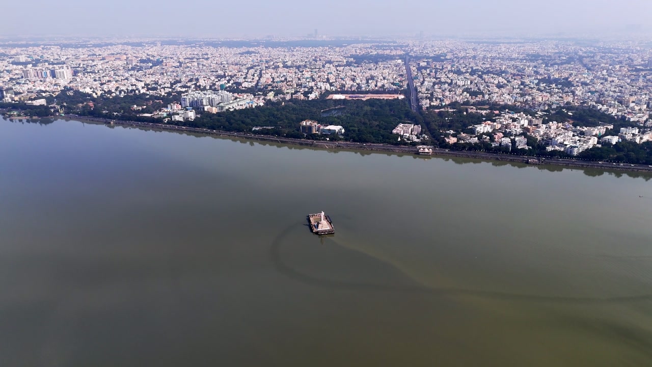 A beautiful aerial sunrise over the Indian city of Hyderabad cinematic footage of Hyderabad's most famous area, Hussain Sagar Lake. The sun and clouds reflect over the lake. Buddha Statue of Hyderabad