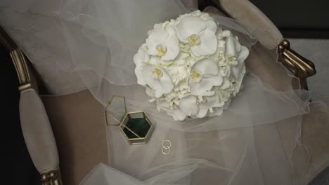 elegant bridal bouquet on veil draped chair with wedding rings and box