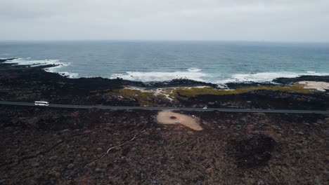 aerial view of volcanic coastline, wavy ocean and straight road