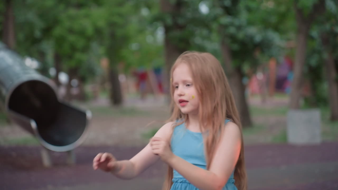 little girl pushes friend on wooden chain swing in blurred playground setting under soft evening light capturing joyful laughter and carefree motion among lush green trees during warm summer park