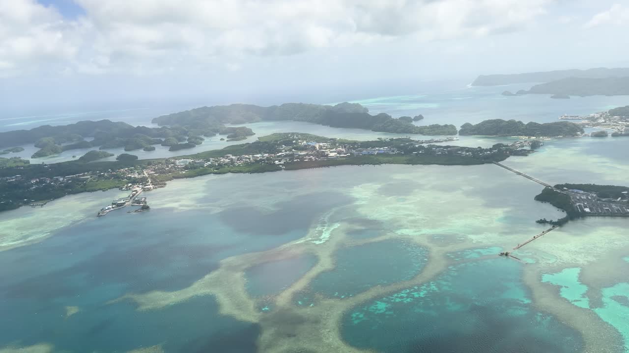 Ripresa aerea con drone ad alta quota sopra acque turchesi e isole calcaree lussureggianti sotto la luce intensa del sole.