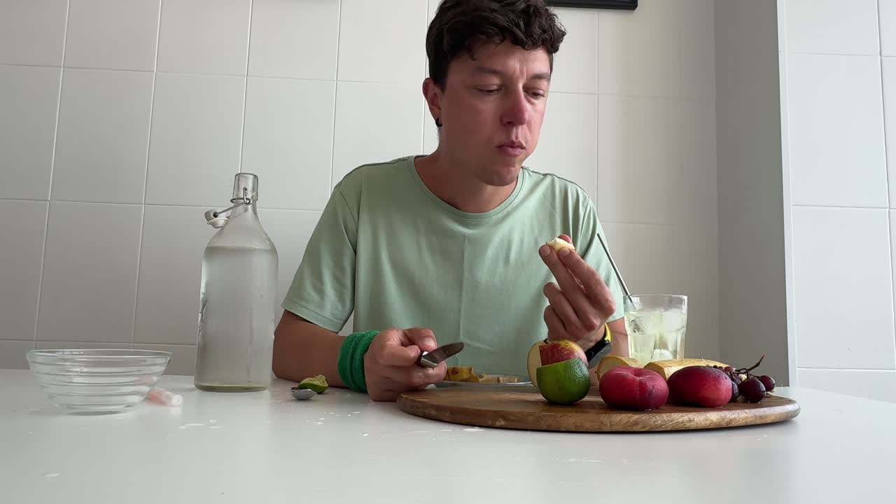Uomo che taglia e mangia frutta fresca a tavola