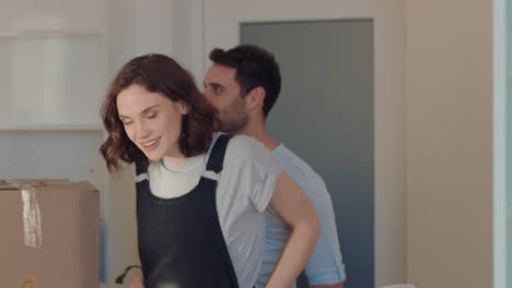 pareja joven mudándose de casa nuevos dueños de casa sonriendo disfrutando de una mudanza exitosa abrazándose en el apartamento