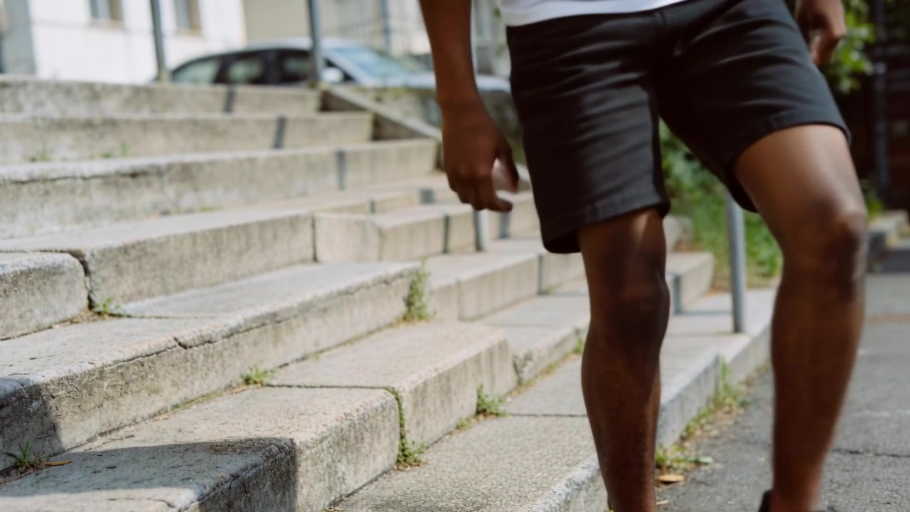 Smiling at friend teen in white tee, black shorts pushing up from concrete steps, walking away