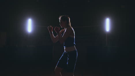 Eine-Starke-Athletische-Boxerin,-Die-Beim-Training-Auf-Schwarzem-Hintergrund-Boxt.-Sportboxkonzept-Mit-Kopierraum.