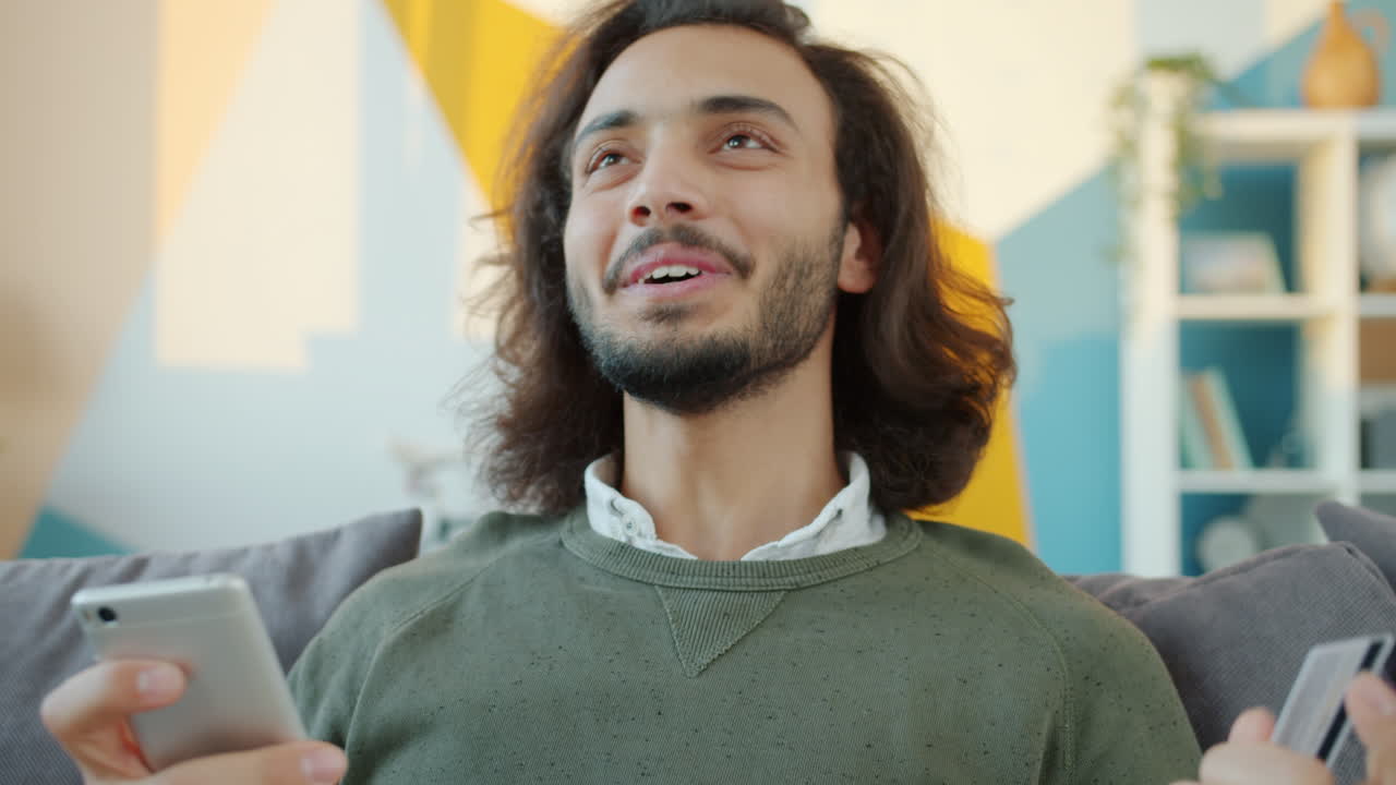 hombre usando teléfono móvil y tarjeta de crédito para comprar en línea en casa