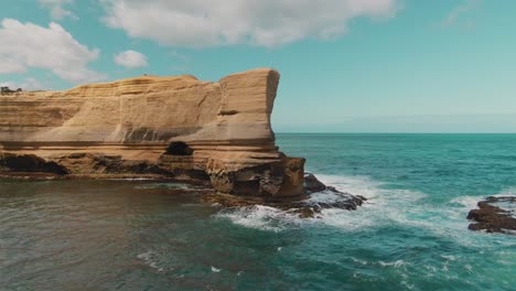 4k aerial big rock with an arch in the ocean near coast