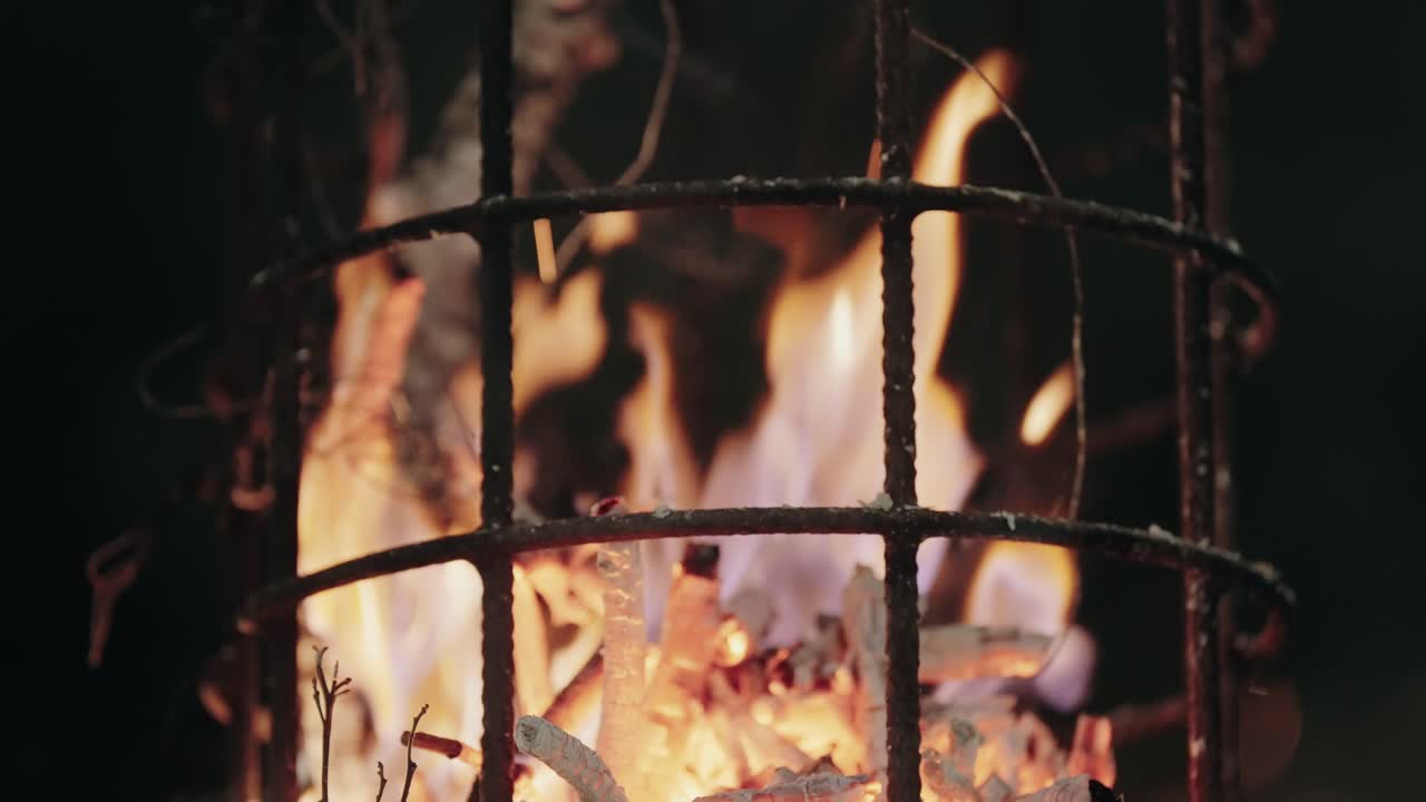 hot embers glow as fire consumes wood within metal torch structure