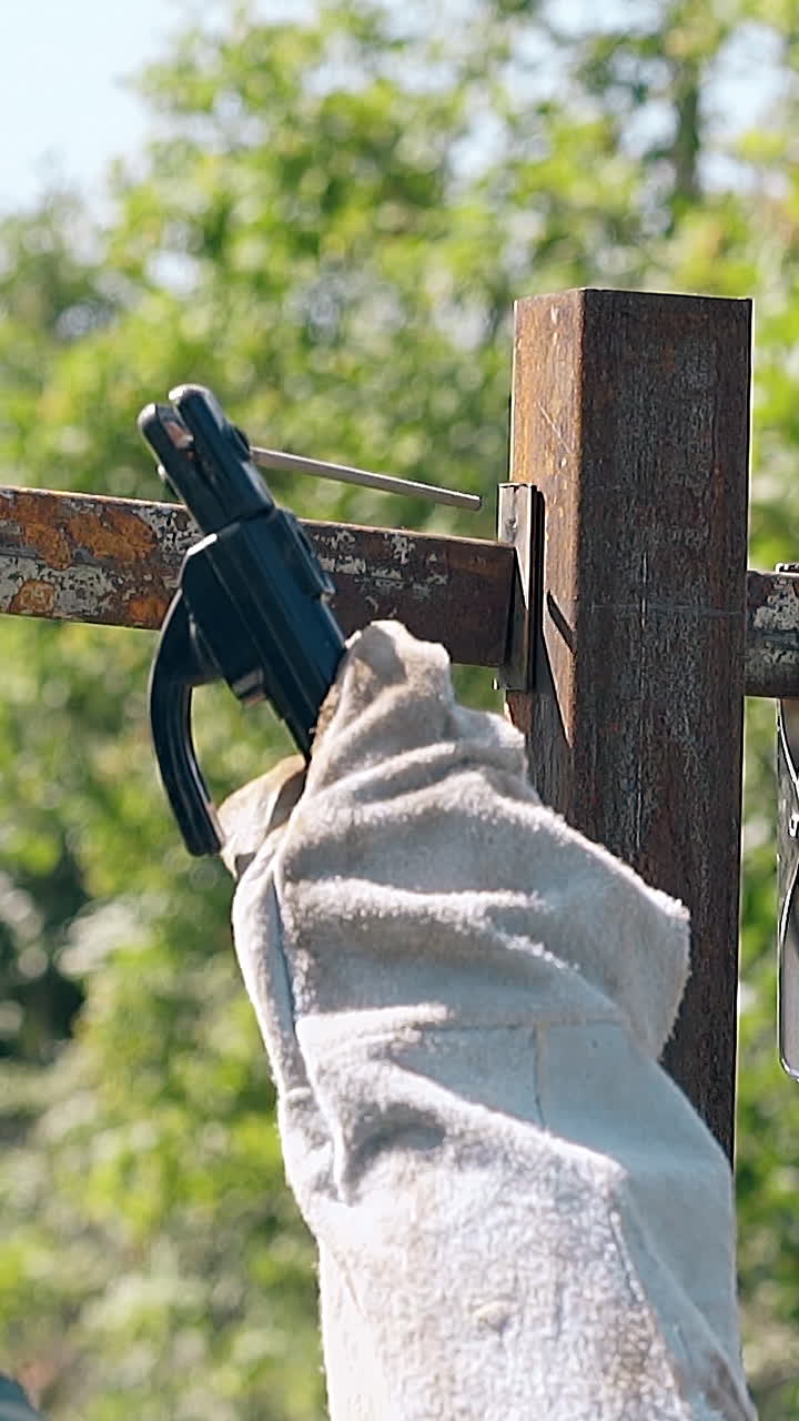slow motion backside view man in protective mask and gloves unwelds old metal plank from fence