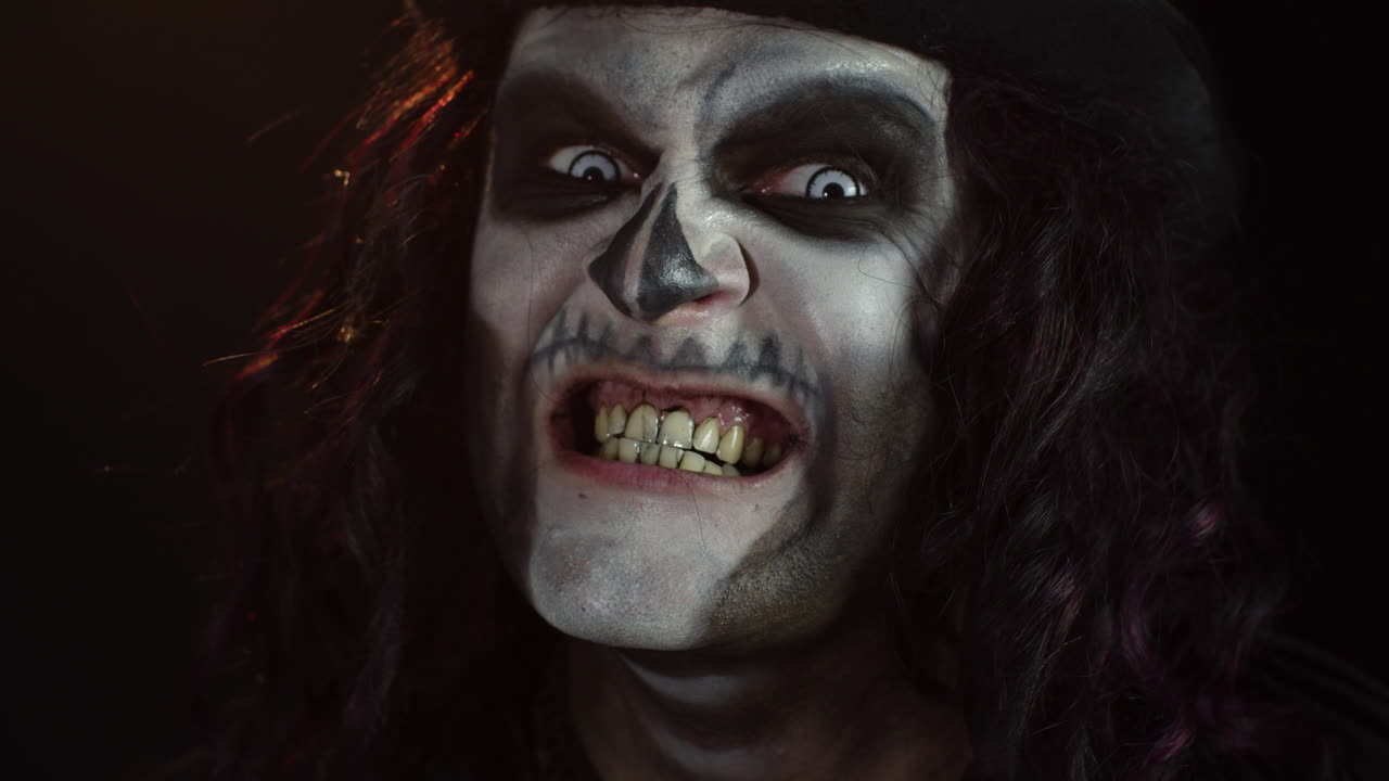 Frightening man in skeleton Halloween makeup screaming, shouting, making faces, trying to scare