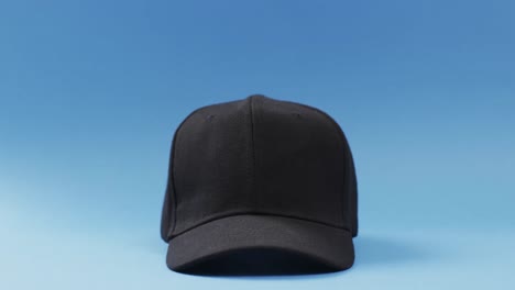 Video-of-black-baseball-cap-and-copy-space-on-blue-background