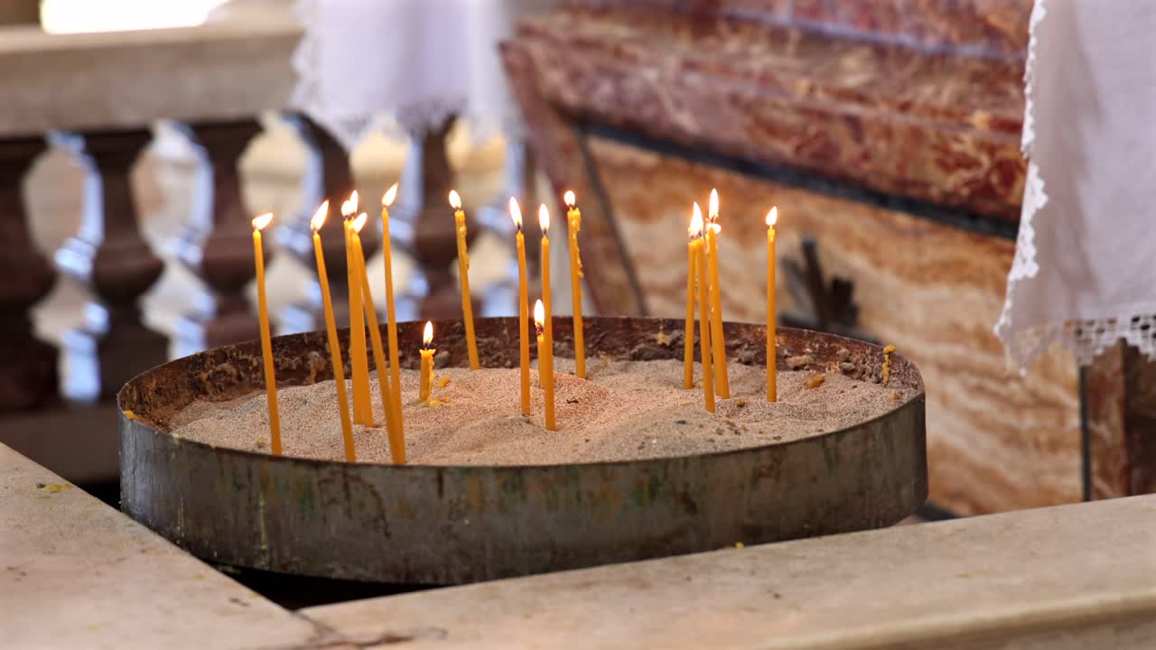 Close-up hand lighting candles in historic Roman Catholic church