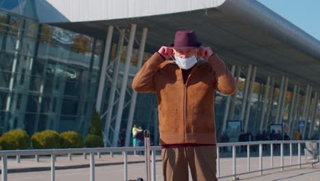 senior pensioner tourist grandfather wearing protective face mask, avoid coronavirus near airport