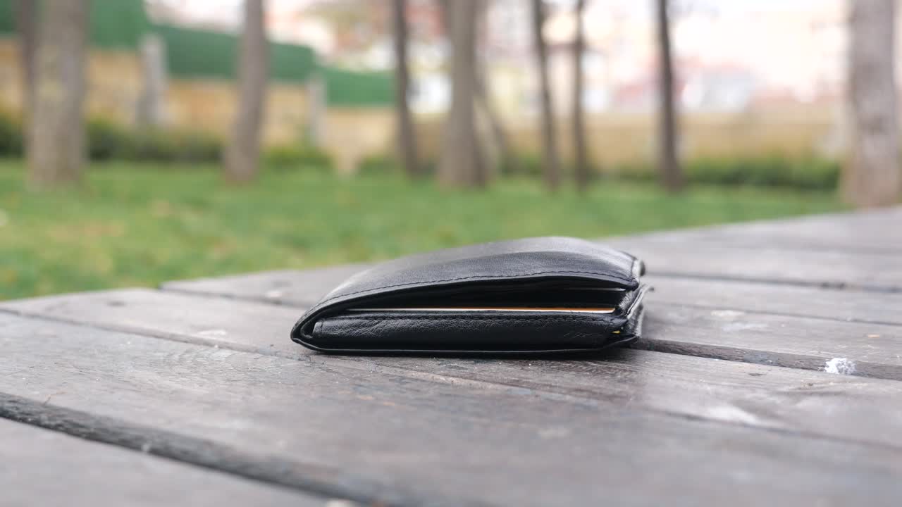 Verlorene schwarze Geldbörse auf einer Parkbank.